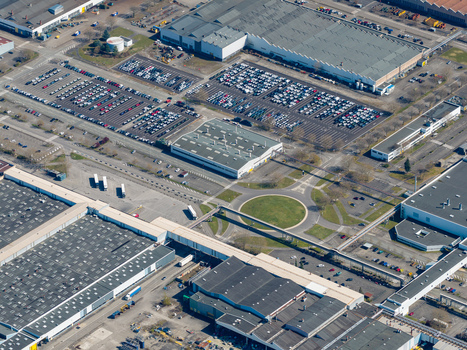 Aerial view of a sprawling industrial landscape with geometric buildings orderly parking lots and a central green roundabout Sausheim Grand Est France.