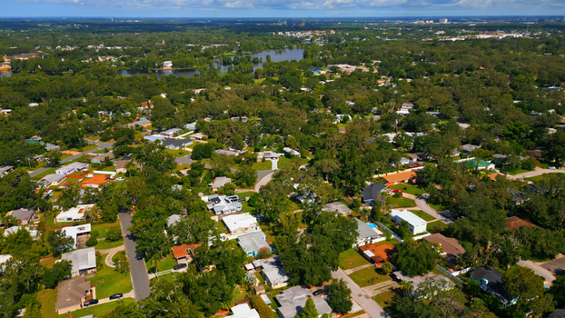 Aerial view of a residential neighborhood with lush green trees suburban houses and a small lake in the background in Tampa Florida United States. Aerial view of a residential neighborhood with lush green trees suburban houses and a small lake in the background in Tampa Florida United States.