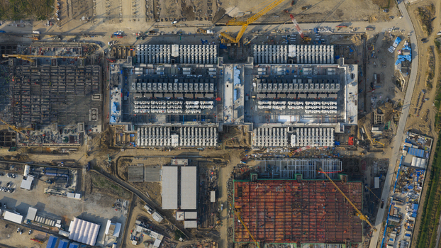 Aerial view of Bridge Data Center under construction showing industrial structures cooling systems and yellow cranes on a large site Khlong Tamru Chon Buri Thailand. Aerial view of Bridge Data Center under construction showing industrial structures cooling systems and yellow cranes on a large site Khlong Tamru Chon Buri Thailand.