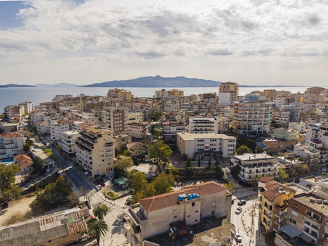 Aerial view of the coastal city with its dense urban architecture residential buildings and streets overlooking the Ionian Sea in Saranda Vlore County Albania. Aerial view of the coastal city with its dense urban architecture residential buildings and streets overlooking the Ionian Sea in Saranda Vlore County Albania.