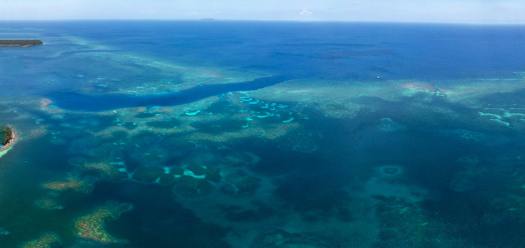 Aerial view of the vibrant coral reef system and turquoise waters surrounding the tropical island of Guanaja Bay Islands Department Honduras. Aerial view of the vibrant coral reef system and turquoise waters surrounding the tropical island of Guanaja Bay Islands Department Honduras.