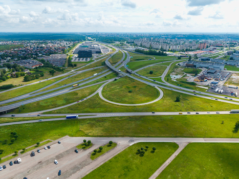 Aerial view of the highway interchange in Kaunas with surrounding green fields roads and urban infrastructure in Kaunas Kaunas County Lithuania.