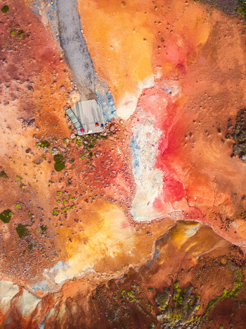 Aerial view of vibrant geothermal landscape with colorful mineral deposits red and orange soil and a small wooden viewing platform in Iceland. Aerial view of vibrant geothermal landscape with colorful mineral deposits red and orange soil and a small wooden viewing platform in Iceland.