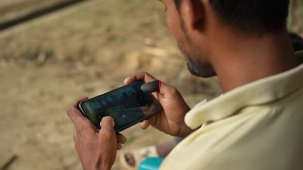 View of a man playing a mobile game with finger sleeves Bangladesh. View of a man playing a mobile game with finger sleeves Bangladesh.