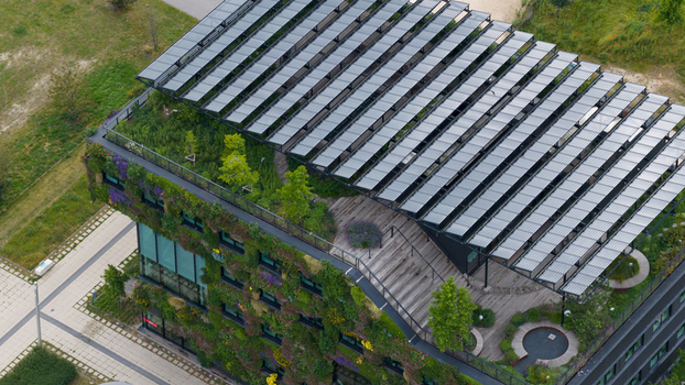 Aerial view of a modern sustainable building featuring a lush green roof with solar panels and a vertical garden facade Almere Flevoland Netherlands. Aerial view of a modern sustainable building featuring a lush green roof with solar panels and a vertical garden facade Almere Flevoland Netherlands.