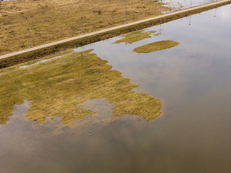 Aerial view of a flooded field and a straight road with lamp posts reflecting in the calm water Kedainiai Kaunas County Lithuania. Aerial view of a flooded field and a straight road with lamp posts reflecting in the calm water Kedainiai Kaunas County Lithuania.