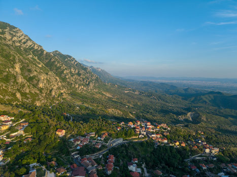 Aerial view of the mountain village of Kruje with red roofed houses nestled on lush green slopes against rocky peaks Kruje Durres County Albania.