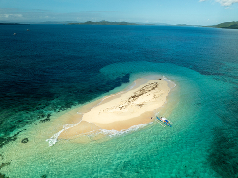 Aerial view of Naked Island surrounded by turquoise waters and a small boat in Siargao Philippines. Aerial view of Naked Island surrounded by turquoise waters and a small boat in Siargao Philippines.