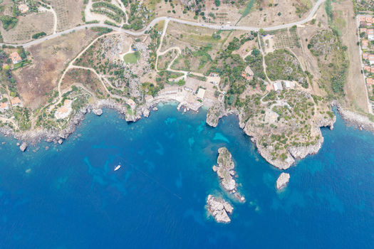 Aerial view of Riserva Naturale Orientata dello Zingaro featuring rugged cliffs turquoise waters and a small cove in San Vito Lo Capo Sicilia Italy. Aerial view of Riserva Naturale Orientata dello Zingaro featuring rugged cliffs turquoise waters and a small cove in San Vito Lo Capo Sicilia Italy.