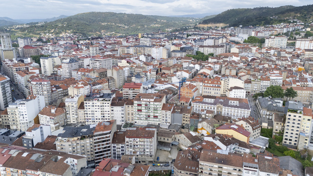 Aerial view of the dense urban landscape with apartment buildings and red tiled rooftops against green hills in Ourense Province of Ourense Spain.