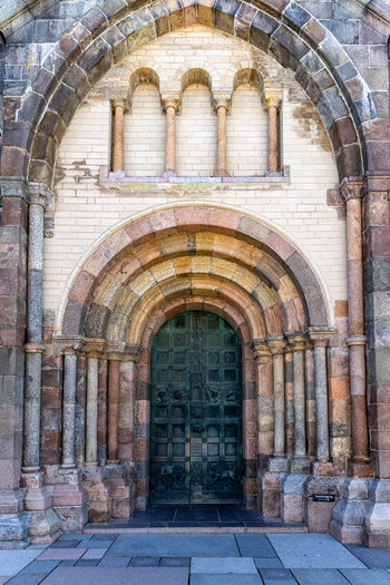 View of the ornate Romanesque portal of Ribe Cathedral with its green bronze door and multi colored stone arches in Ribe Denmark. View of the ornate Romanesque portal of Ribe Cathedral with its green bronze door and multi colored stone arches in Ribe Denmark.