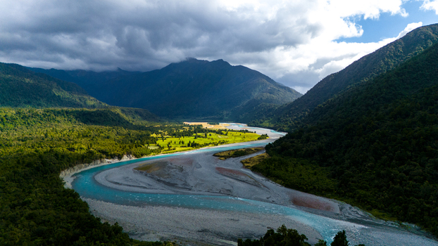 Aerial view of the Hokitika River snaking through lush green forests and mountains under a cloudy sky Hokitika Gorge West Coast Region New Zealand. Aerial view of the Hokitika River snaking through lush green forests and mountains under a cloudy sky Hokitika Gorge West Coast Region New Zealand.