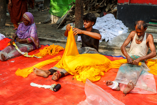 Narayanganj Bangladesh 29 March 2026 View of vibrant yellow fabric being handled by workers outdoors creating a striking contrast against the weathered ground. Narayanganj Bangladesh 29 March 2026 View of vibrant yellow fabric being handled by workers outdoors creating a striking contrast against the weathered ground.