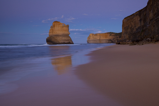 View of limestone stacks of the Twelve Apostles at twilight with gentle waves washing onto the sandy beach and steep cliffs in Australia. View of limestone stacks of the Twelve Apostles at twilight with gentle waves washing onto the sandy beach and steep cliffs in Australia.
