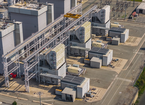 Aerial view of large heat recovery steam generator units industrial buildings and power infrastructure at a modern combined cycle facility in Chivasso Piedmont Italy.