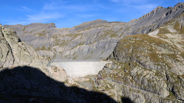 View of the Vieux Emosson Dam nestled within the rugged rocky peaks of the Swiss Alps under a clear blue sky in Finhaut Valais Switzerland. View of the Vieux Emosson Dam nestled within the rugged rocky peaks of the Swiss Alps under a clear blue sky in Finhaut Valais Switzerland.