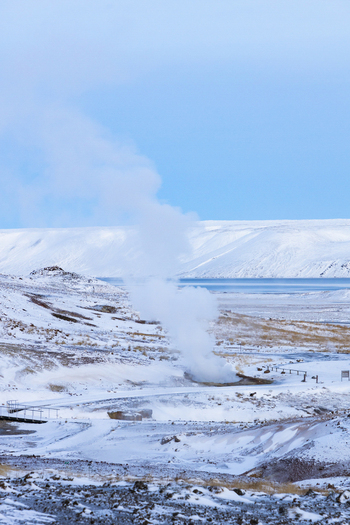 View of geothermal steam rising from the snowy rugged landscape under a pastel sky creating a surreal and ethereal scene Selt&uacute;n Hafnarfjar&eth;arkaupsta&eth;ur Iceland.