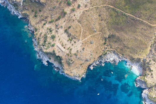 Aerial view of Riserva Naturale Orientata dello Zingaro featuring rugged coastal cliffs turquoise Mediterranean waters hiking trails and small boats in San Vito Lo Capo Sicilia Italy. Aerial view of Riserva Naturale Orientata dello Zingaro featuring rugged coastal cliffs turquoise Mediterranean waters hiking trails and small boats in San Vito Lo Capo Sicilia Italy.