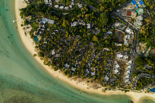 Aerial view of a luxury coastal resort with a white sand beach turquoise lagoon lush tropical vegetation and private villas with swimming pools in Moka District Mauritius. Aerial view of a luxury coastal resort with a white sand beach turquoise lagoon lush tropical vegetation and private villas with swimming pools in Moka District Mauritius.