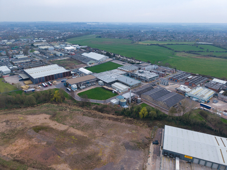 Aerial view of industrial buildings nestled near fields a blend of gray structures and green spaces under an overcast sky Redditch United Kingdom. Aerial view of industrial buildings nestled near fields a blend of gray structures and green spaces under an overcast sky Redditch United Kingdom.