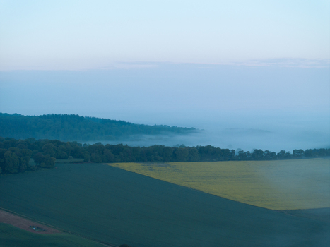 Aerial view of rolling hills and vibrant yellow rapeseed fields shrouded in morning mist and dense forests Nuffield Oxfordshire United Kingdom. Aerial view of rolling hills and vibrant yellow rapeseed fields shrouded in morning mist and dense forests Nuffield Oxfordshire United Kingdom.