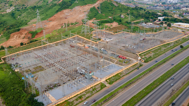 Aerial view of TCN SubStation Katampe featuring electrical transformers metal structures and power lines near a highway and green hills in Abuja Federal Capital Territory Nigeria.