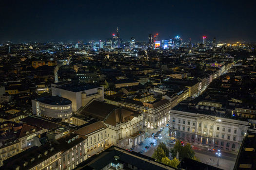 Milan Italy 23 September 2026 Aerial view of the illuminated La Scala opera house and the surrounding historic city center with the modern skyline glowing in the background at night. Milan Italy 23 September 2026 Aerial view of the illuminated La Scala opera house and the surrounding historic city center with the modern skyline glowing in the background at night.