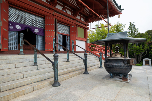 View of a traditional Japanese temple with vibrant red accents contrasting against the serene grey stone steps and lush greenery Narita Chiba Japan. View of a traditional Japanese temple with vibrant red accents contrasting against the serene grey stone steps and lush greenery Narita Chiba Japan.