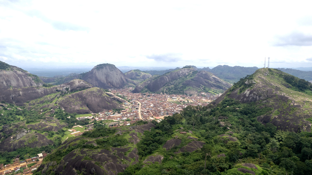 Aerial view of the dramatic rocky landscape of Idanre Hill featuring massive granite inselbergs lush green vegetation and the town nestled in the valley in Idanre Ondo State Nigeria. Aerial view of the dramatic rocky landscape of Idanre Hill featuring massive granite inselbergs lush green vegetation and the town nestled in the valley in Idanre Ondo State Nigeria.