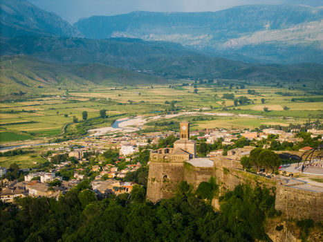 Aerial view of Gjirokaster Fortress featuring the historic clock tower and stone fortifications overlooking the Drino Valley in Gjirokaster Gjirokaster County Albania. Aerial view of Gjirokaster Fortress featuring the historic clock tower and stone fortifications overlooking the Drino Valley in Gjirokaster Gjirokaster County Albania.
