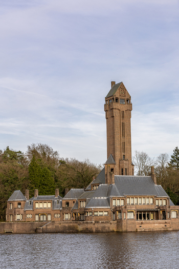 View of Country Residence Museum Jachthuis Sint Hubertus with its iconic tall tower and brick architecture by the water in Hoenderloo Gelderland Netherlands.