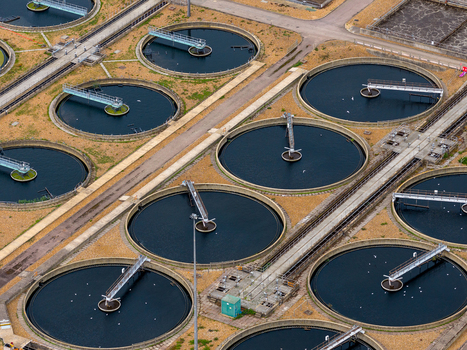 Aerial view of a water treatment plant featuring multiple circular sedimentation tanks with rotating mechanical arms and connecting walkways in Broughton England United Kingdom. Aerial view of a water treatment plant featuring multiple circular sedimentation tanks with rotating mechanical arms and connecting walkways in Broughton England United Kingdom.