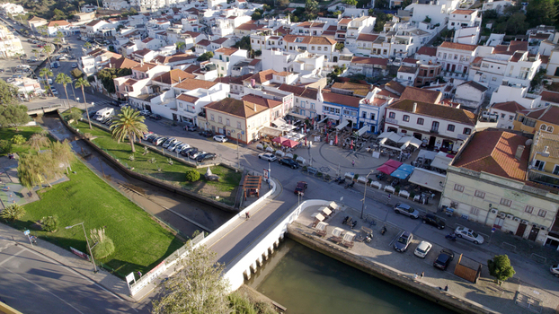 Aerial view of the historic town of Ferragudo featuring white washed buildings a central square a bridge over a river and parked cars in Ferragudo Faro District Portugal.