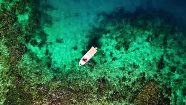 Aerial view of a small boat over coral reefs in turquoise water Honduras. Aerial view of a small boat over coral reefs in turquoise water Honduras.
