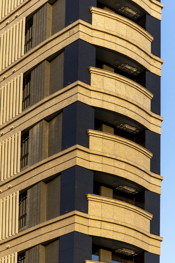 View of modern residential building facade with curved balconies and stone textures under a clear blue sky Taipei City Taiwan. View of modern residential building facade with curved balconies and stone textures under a clear blue sky Taipei City Taiwan.