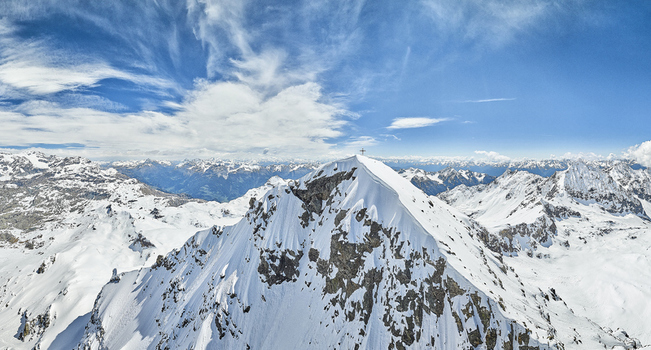 Aerial view of the snow covered peak of Valmalenco with a summit cross under a bright blue sky in Lombardia Italia. Aerial view of the snow covered peak of Valmalenco with a summit cross under a bright blue sky in Lombardia Italia.