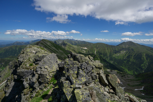 View of Tri kopy in Western Tatras featuring sharp rocky ridges and green alpine meadows under a blue sky with white clouds in Ziar Zilina Region Slovakia. View of Tri kopy in Western Tatras featuring sharp rocky ridges and green alpine meadows under a blue sky with white clouds in Ziar Zilina Region Slovakia.