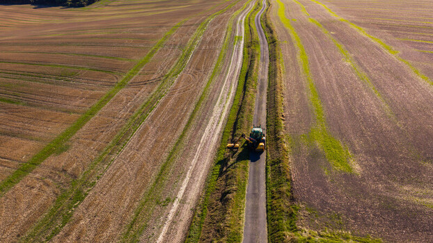 Aerial view of a tractor trimming hedges along a narrow country road through agricultural fields at Pepperbox Hill Salisbury England United Kingdom. Aerial view of a tractor trimming hedges along a narrow country road through agricultural fields at Pepperbox Hill Salisbury England United Kingdom.