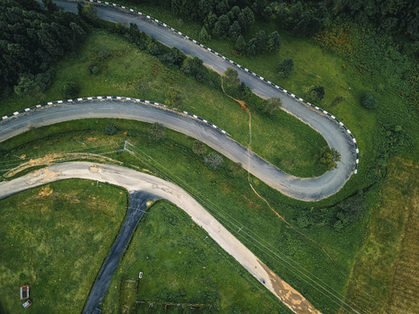 Aerial view of a ribbon of asphalt winding dramatically through vibrant emerald hills and dense dark green forests Obudu Cross River Nigeria.