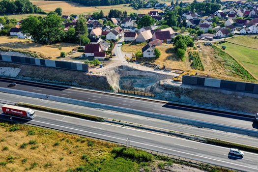 Nurnberg Germany 18 May 2024 Aerial view of the A73 highway construction site with excavators and noise barriers near a residential village. Nurnberg Germany 18 May 2024 Aerial view of the A73 highway construction site with excavators and noise barriers near a residential village.