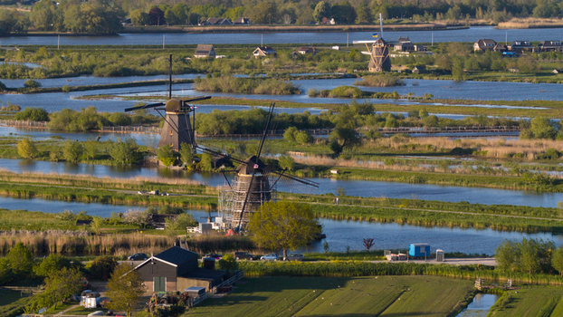 Aerial view of the historic windmills standing along blue canals and lush green fields under a clear sky in Kinderdijk South Holland Netherlands. Aerial view of the historic windmills standing along blue canals and lush green fields under a clear sky in Kinderdijk South Holland Netherlands.
