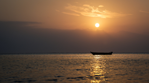View of a lone boat silhouetted against the shimmering golden sea under a serene sun kissed sky creating a tranquil coastal scene Paje Tanzania. View of a lone boat silhouetted against the shimmering golden sea under a serene sun kissed sky creating a tranquil coastal scene Paje Tanzania.