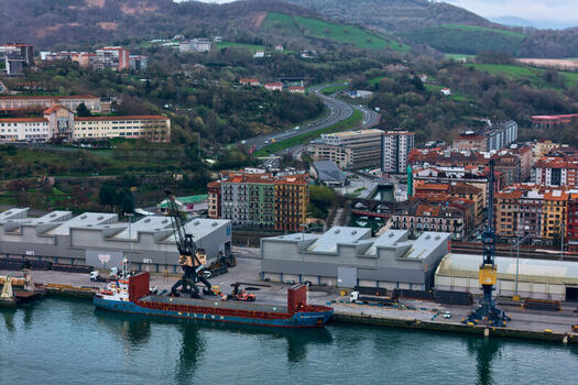 Pasai Donibane Spain 09 March 2026 Aerial view of Puerto Pasajes with a cargo ship docked at the pier industrial warehouses and the surrounding urban landscape. Pasai Donibane Spain 09 March 2026 Aerial view of Puerto Pasajes with a cargo ship docked at the pier industrial warehouses and the surrounding urban landscape.