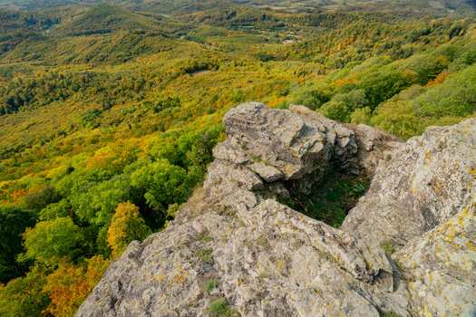 Aerial view of Sitno in Stiavnicke Vrchy with rocky cliffs overlooking the vibrant autumn forest canopy in Ilija Banska Bystrica Region Slovakia.