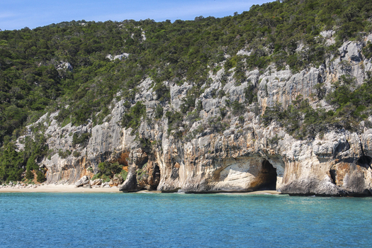 View of the Gulf of Orosei featuring dramatic limestone cliffs sea caves and turquoise Mediterranean waters in Italy. View of the Gulf of Orosei featuring dramatic limestone cliffs sea caves and turquoise Mediterranean waters in Italy.