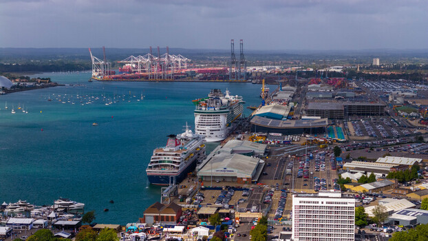 Aerial view of large cruise ships docked at the busy Southampton port with container cranes in the background and surrounding industrial infrastructure in Southampton England United Kingdom. Aerial view of large cruise ships docked at the busy Southampton port with container cranes in the background and surrounding industrial infrastructure in Southampton England United Kingdom.