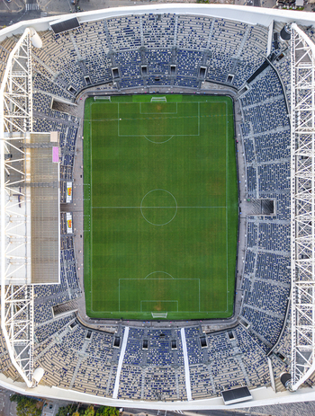 Aerial view of Bloomfield Stadium featuring a green soccer pitch surrounded by blue seating and structural roof supports in Tel Aviv Yafo Tel Aviv District Israel. Aerial view of Bloomfield Stadium featuring a green soccer pitch surrounded by blue seating and structural roof supports in Tel Aviv Yafo Tel Aviv District Israel.