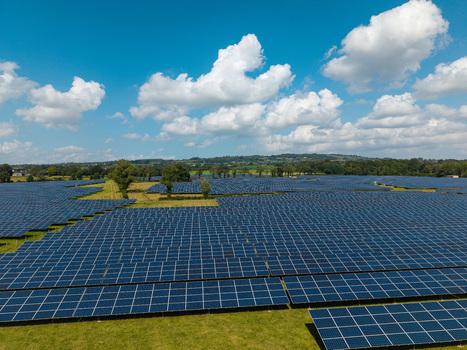 Aerial view of Lisburn Solar Farm featuring rows of photovoltaic panels set in green fields under a blue sky with white clouds in Lisburn Northern Ireland United Kingdom. Aerial view of Lisburn Solar Farm featuring rows of photovoltaic panels set in green fields under a blue sky with white clouds in Lisburn Northern Ireland United Kingdom.