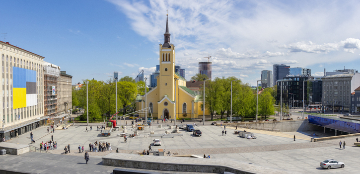 Tallinn Estonia 16 May 2026 View of Freedom Square with St. John s Church people walking across the paved plaza and modern city skyline under a clear blue sky.