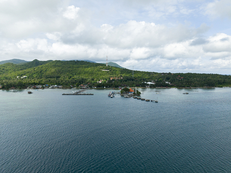 Aerial view of the Karimunjawa ferry harbour where boats bob gently on the tranquil turquoise sea against the verdant backdrop of the island Karimunjawa Jawa Tengah Indonesia. Aerial view of the Karimunjawa ferry harbour where boats bob gently on the tranquil turquoise sea against the verdant backdrop of the island Karimunjawa Jawa Tengah Indonesia.